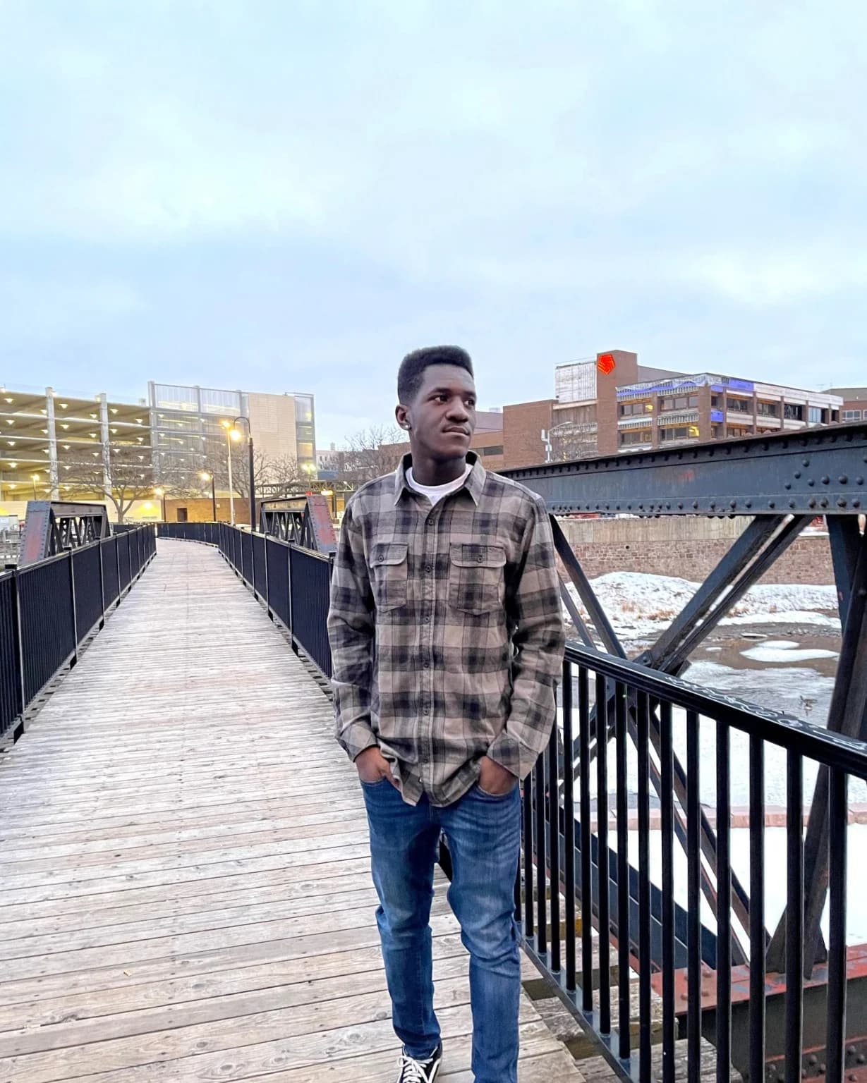 Wilson standing on a pedestrian bridge in a city setting during winter.